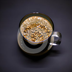 Hot black coffee in a ceramic cup and crystals of instant coffee on a dark gray background.