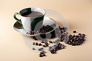 Hot black coffee in green coffee cup and coffee beans on a brown Klang background
