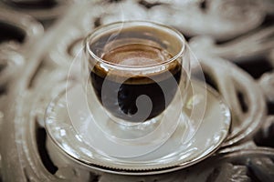 Hot black coffee on outdoor table in a transparent glass.