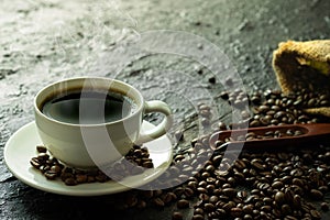 Hot black coffee with smoke for morning beverage menu in white ceramic cup with coffee beans roasted