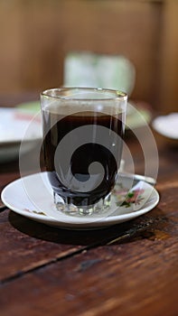 Hot black coffee in a traditional Javanese glass called starfruit glass or gelas belimbing