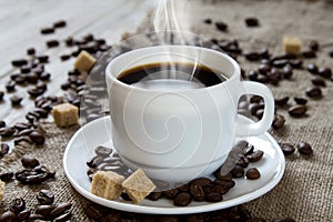 Hot black coffee in a white cup, cane sugar and roasted beans