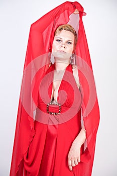 Hot blonde caucasian woman wearing long red evening dress and posing on white studio background alone. fashionable adult girl with