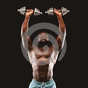 Hot bodybuilder lifting dumbbells up over black background