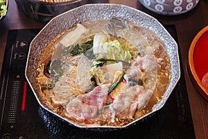 Hot and Boiling Shabu broth with cabbage, eryngii, enotitake, tofu and Kurobuta pork inside hot pot