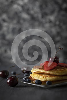 Hot cakes with strawberries and cherries seen from close up photo