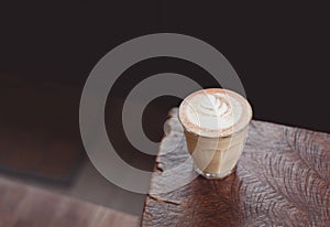 Hot cappuccino coffee cup on wooden tray with latte art on wood