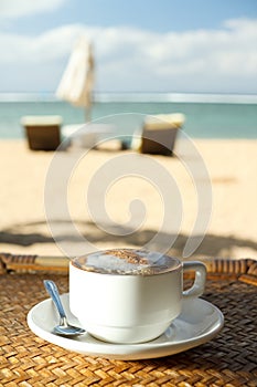 Hot cappuccino coffee at tropical beach