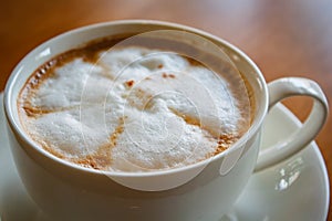 Hot cappuccino cup on wood table.