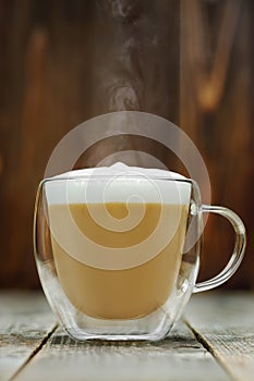 hot cappuccino in glass cup on grey wooden table