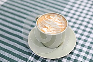 hot cappuccino with latte art on wood background in closeup