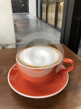 Hot cappuccino with milk foam on wood table in coffee shop