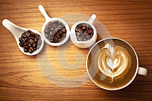 Hot cappuccino with roasted coffee beans on a wooden background and free space