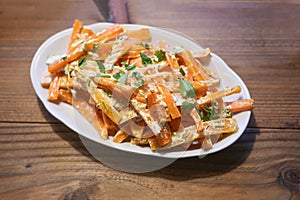 Hot carrot strips with a creamy spicy dressing and parsley garnish, healthy cold tapa snack for a Mediterranean buffet on a rustic