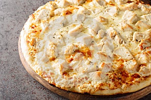 Hot cheese Alfredo pizza with chicken close-up on a wooden board. Horizontal