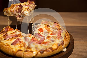 Hot cheese pizza in dinner light on wood table