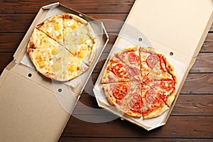 Hot cheese pizzas in cardboard boxes on table, top view. Food delivery service photo