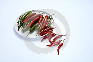 Hot chili pepper green and red in a white plate on a white background.