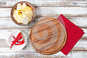 Hot chili pepper on plate,cutting pizza desk,red napkin and potato chips on table, copy space,top view