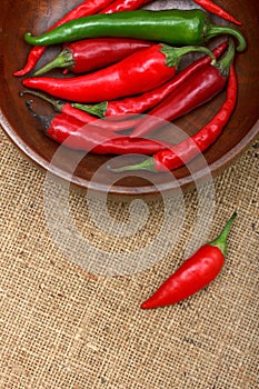 Hot chili peppers in wooden bowl over canvas