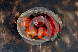 hot chili sauce, fresh tomatoes on tray with dark wooden background