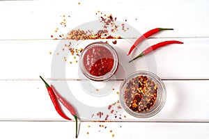 Hot chilli pepper sauce paste harissa, adjika ,chili pepper spices and fresh red chilli peppers, over wooden background