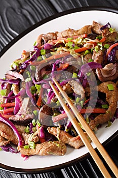 Hot chinese pork moo shu with vegetables close-up in a plate. vertical