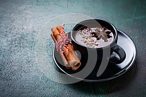 Hot chocolate with anise and nuts in black ceramic cup on old dark green concrete background. Selective focus