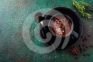 Hot chocolate with anise and nuts in black ceramic cup on old dark green concrete background. Selective focus