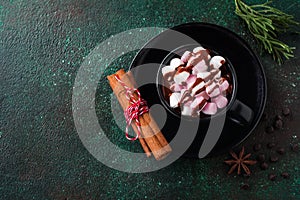 Hot chocolate with anise and nuts in black ceramic cup on old dark green concrete background. Selective focus