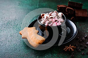 Hot chocolate with anise and nuts in black ceramic cup on old dark green concrete background. Selective focus