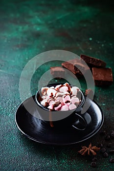 Hot chocolate with anise and nuts in black ceramic cup on old dark green concrete background. Selective focus