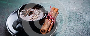 Hot chocolate with anise and nuts in black ceramic cup on old dark green concrete background. Selective focus