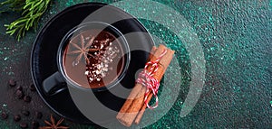 Hot chocolate with anise and nuts in black ceramic cup on old dark green concrete background. Selective focus