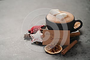 Hot chocolate in a black cup with christmas decorations and paper card