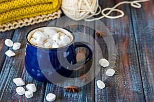 Hot chocolate or cacao in a blue mug with marshmallows on the ta