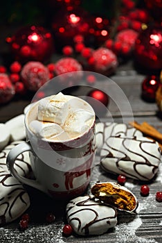 Hot chocolate or cocoa beverage with cinnamon and gingerbread cookies in snow vintage wooden table background.