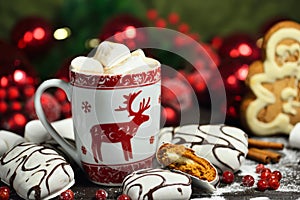 Hot chocolate or cocoa beverage with cinnamon and gingerbread cookies in snow vintage wooden table background.