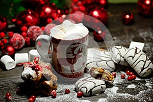 Hot chocolate or cocoa beverage with cinnamon and gingerbread cookies in snow vintage wooden table background.