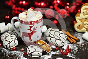 Hot chocolate or cocoa beverage with cinnamon and gingerbread cookies in snow vintage wooden table background.