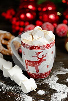 Hot chocolate or cocoa beverage with cinnamon and gingerbread cookies in snowon vintage wooden table background.