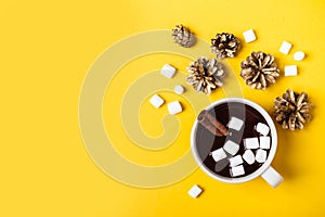 Hot chocolate cup with cinnamon and marshmallow on yellow background. Warming Christmas winter drink