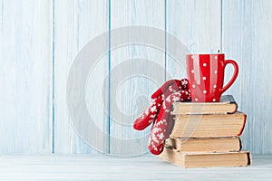 Hot chocolate cup and mittens over books