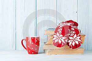 Hot chocolate cup and mittens over books