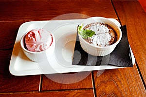 Hot chocolate cupcake fondant with scoop or ball of strawberry ice cream on wooden table. Close-up, top view