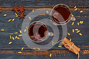 Hot chocolate decorated with winter spices - cinnamon and cardamom on the black wooden background