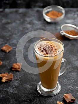 Hot chocolate drink. Tall glass up of fresh coffee latte with whipped cream, isolated on dark background