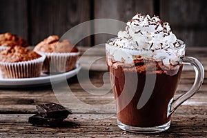 Hot chocolate drink with whipped cream in a glass on a wooden background