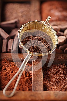 Hot chocolate flakes in old rustic style silver sieve on wooden