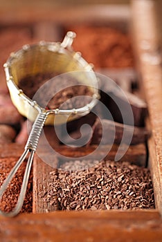 Hot chocolate flakes in old rustic style silver sieve on wooden